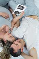 Expecting couple lying on bed