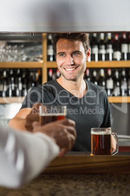 Handsome bar tender giving a pint to customer