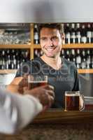 Handsome bar tender giving a pint to customer