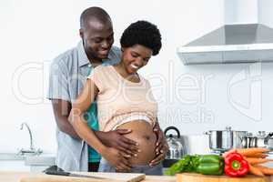 Pregnant couple embracing in kitchen