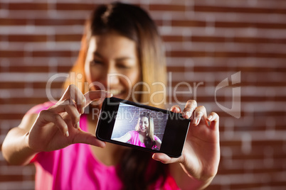 Smiling asian woman taking selfie with smartphone