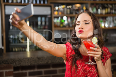 Pretty woman taking a selfie with her cocktail