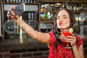 Pretty woman taking a selfie with her cocktail