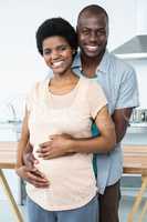 Pregnant couple embracing in kitchen