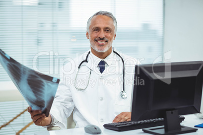 Happy doctor holding x-ray in clinic