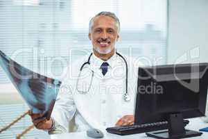 Happy doctor holding x-ray in clinic