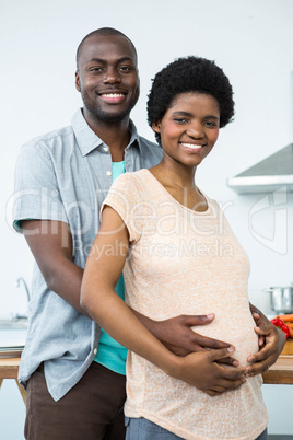 Pregnant couple embracing in kitchen