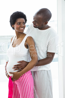 Pregnant couple embracing in bedroom