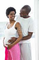 Pregnant couple embracing in bedroom