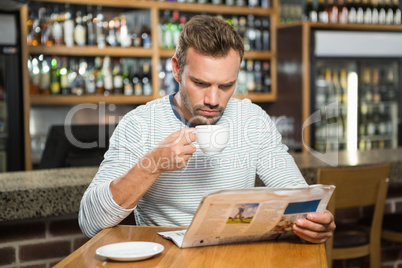 Handsome man reading newspaper and having a coffee