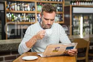 Handsome man reading newspaper and having a coffee