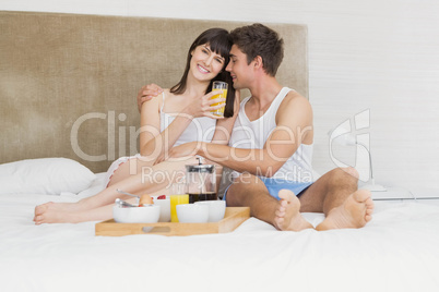 Young couple having breakfast on bed