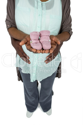 Pregnant couple holding baby shoes