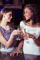 Young women toasting champagne flutes at bar counter
