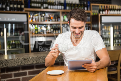 Handsome man using tablet and having coffee