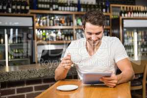 Handsome man using tablet and having coffee