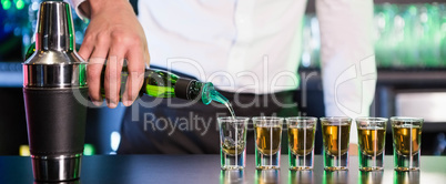 Bartender pouring tequila into shot glasses