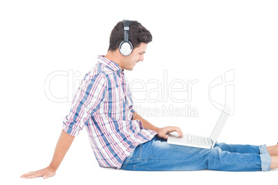 Man with headphones sitting on the floor using laptop