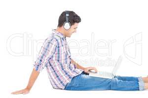 Man with headphones sitting on the floor using laptop
