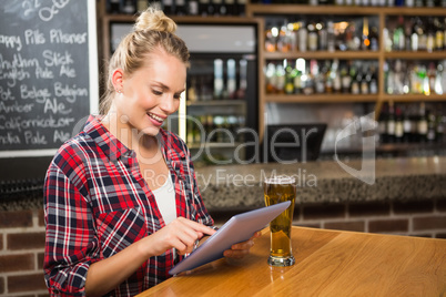 Pretty woman having a beer and looking at tablet