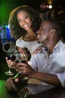 Couple smiling and toasting their wine glasses at bar counter