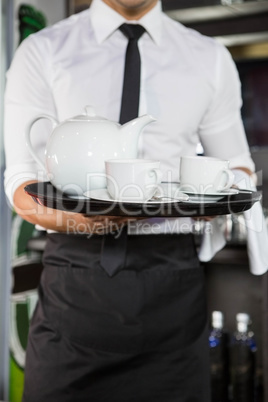 Mid section of waiter serving tea