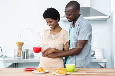 Pregnant couple having breakfast in kitchen