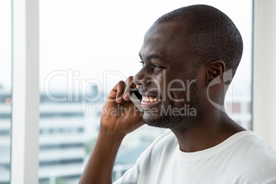 Man talking on mobile phone near window