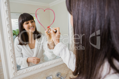 Young beautiful woman drawing big heart on mirror