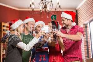 Cute group of friends toasting with santa hats