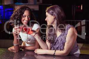 Young women toasting cocktail glasses at bar counter