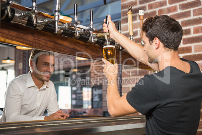 Handsome bar tender pouring a pint for a customer