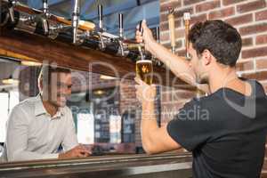 Handsome bar tender pouring a pint for a customer