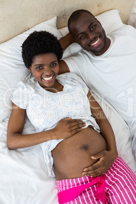 Pregnant couple relaxing on bed