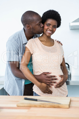 Pregnant couple embracing in kitchen