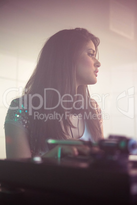 Pretty female DJ looking at audience while playing music