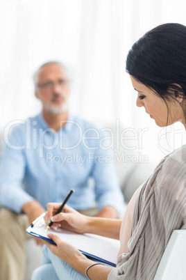 Female doctor writing on clipboard while consulting a man