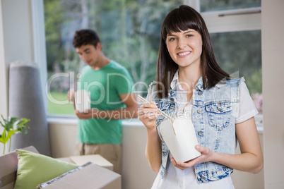 Portrait of young woman eating noodles at home