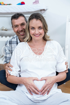 Couple making a heart shape on belly