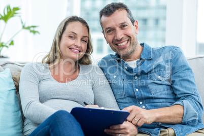 Pregnant woman writing on clipboard