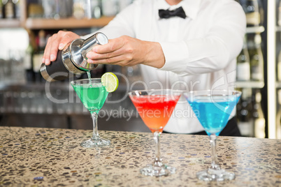 Handsome barman pouring cocktails