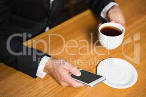 Businessman using smartphone and having coffee