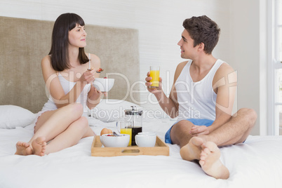 Young couple having breakfast on bed