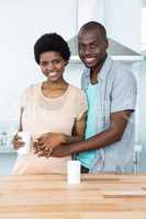 Pregnant couple embracing while having cup of coffee