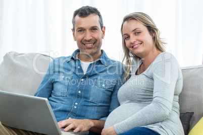 Couple sitting together and using laptop