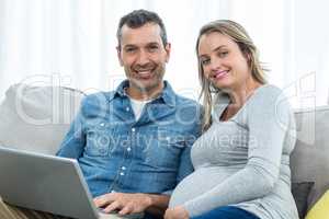 Couple sitting together and using laptop