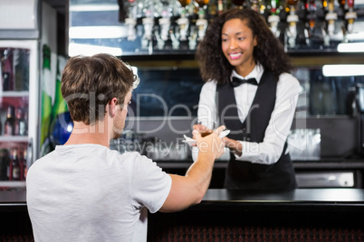 Barmaid serving drink to man