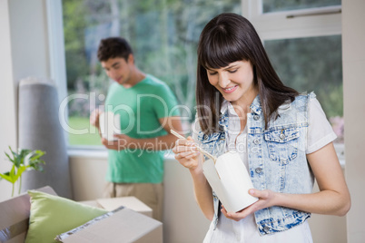 Portrait of young woman eating noodles at home