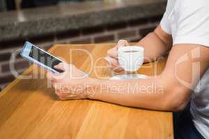 Handsome man using tablet and having coffee