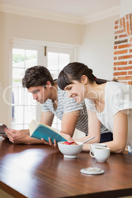 Young couple reading book while having breakfast